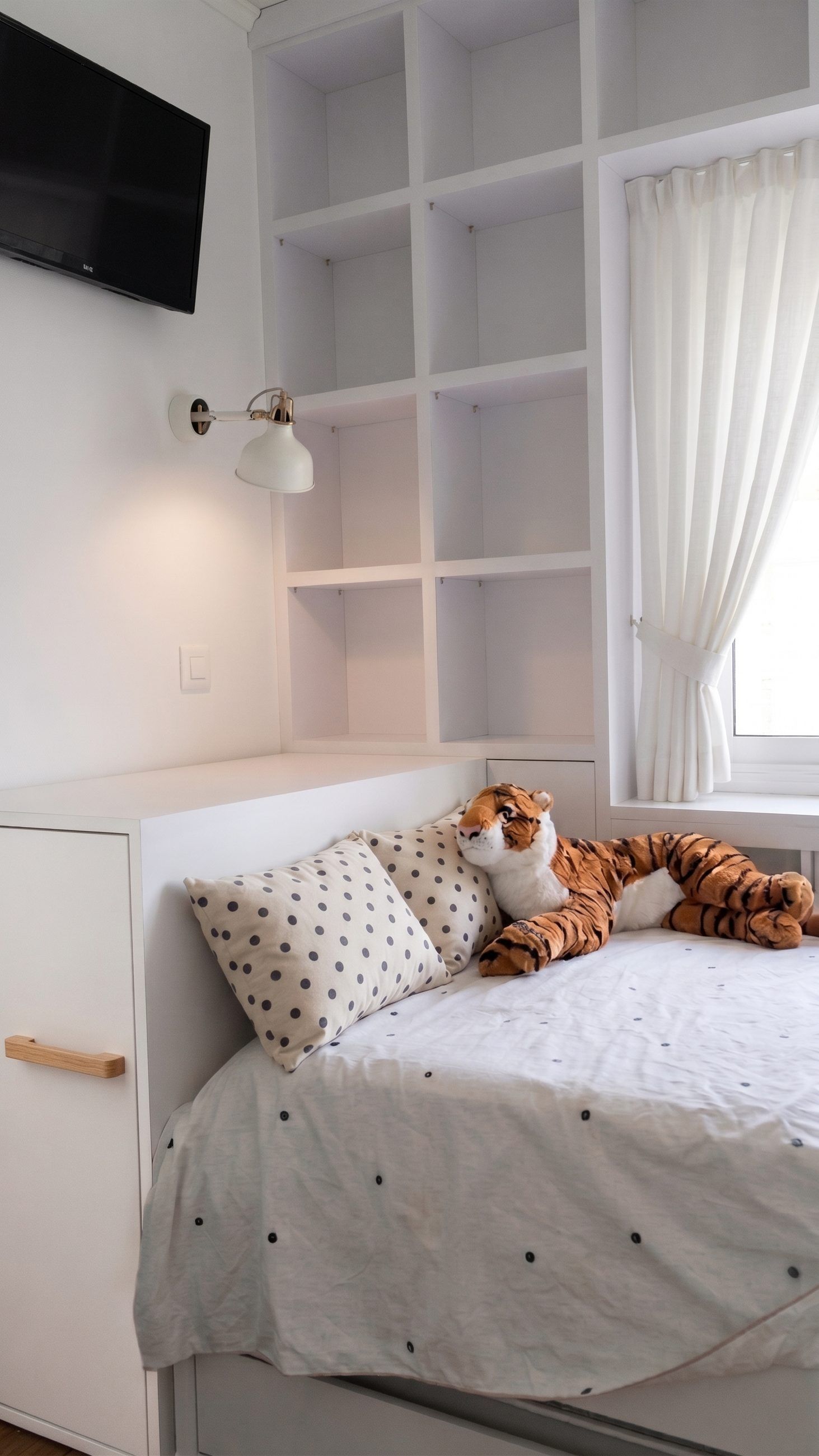Cama con almacenaje integrado y estanterías de suelo a techo junto a la ventana