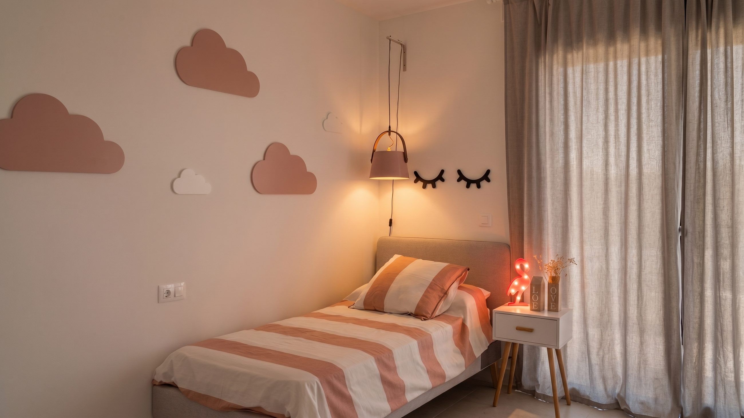 Dormitorio juvenil con cama tapizada, apliques de nubes en la pared y luz cálida