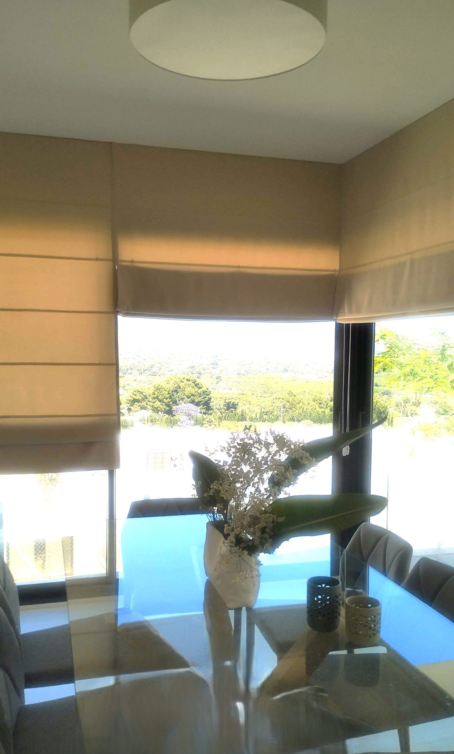Estores romanos de tela beige en un comedor con vistas al campo